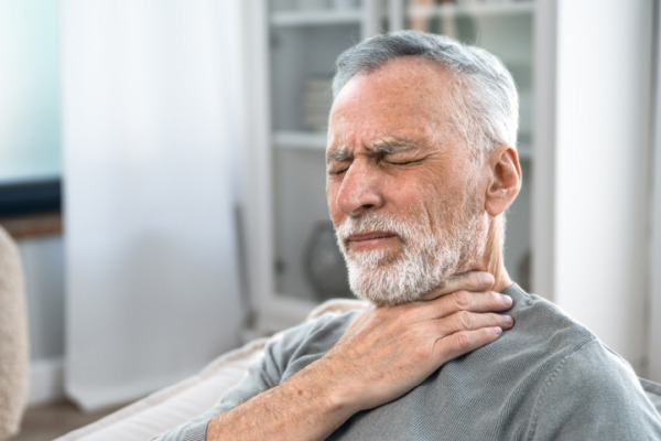 man holding his throat after coughing