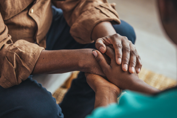 people clasping each other's hands to comfort one another