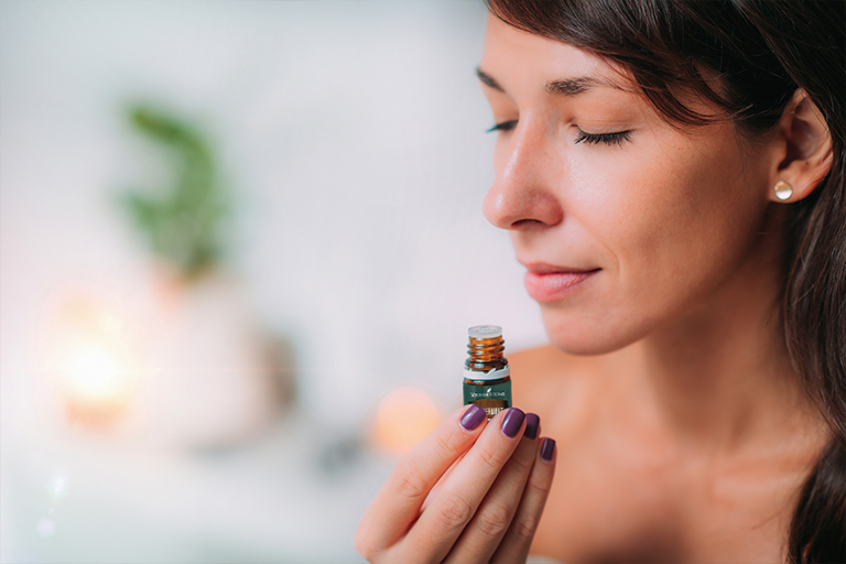 Image of woman inhaling Peppermint essential oil directly from the bottle.