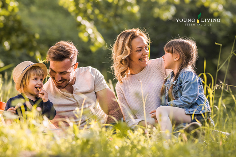 Un padre y una madre llevando de la mano a sus dos hijos pequeños y sonriendo en un campo