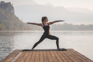 Kvinnor utövar yoga längst ut på en brygga vid vattnet