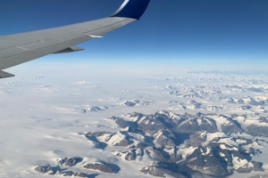 Plane window view with snow-capped landscape below
