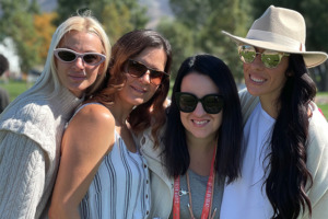 Vier vrouwen met zonnebril glimlachen en poseren voor een foto