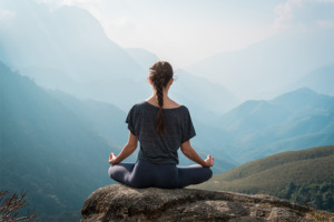 Nainen joogaa, meditoi ja manifestoi vuorilla