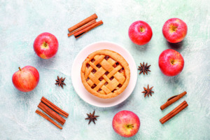 Mini tartas de manzana veganas rodeadas de manzanas, palitos de canela y anís estrellado