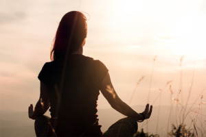 Silhouette of woman practicing yoga at sunset