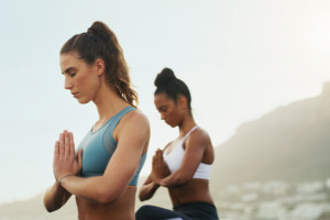 Två kvinnor utövar yoga utomhus