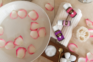 Les huiles essentielles de lavande, de camomille allemande et d’élémi avec des pétales de fleurs, une serviette, un bol d’eau et des sels pour un bain de vapeur pour le visage