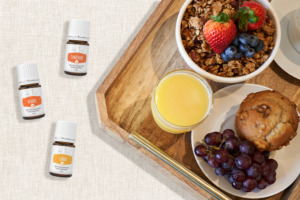 Les huiles essentielles Lemon+, Orange+ et Tangerine+ avec des viennoiseries, des fruits, des céréales et des jus de fruits pour le petit-déjeuner
