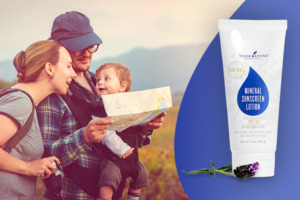 Mutter, Vater und Kleinkind in Rucksacktrage beim Wandern mit Landkarte in der Hand und Young Living Mineral Sunscreen Lotion mit LSF 50