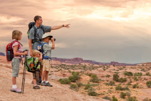 Vater und drei Kinder beim Wandern und Erkunden mit atemberaubender Landschaft im Hintergrund