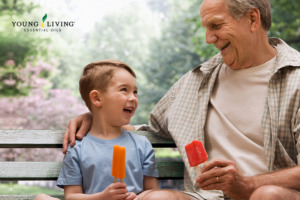 Lachendes Kind mit Großvater und Eis am Stiel auf einer Bank