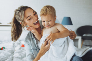Una madre y su bebé envuelto en una toalla sonriendo