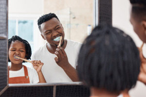 Vater und Tochter vor dem Spiegel beim Zähneputzen