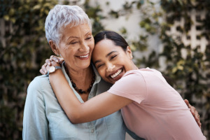 Lachende Enkeltochter und Großmutter die sich umarmen