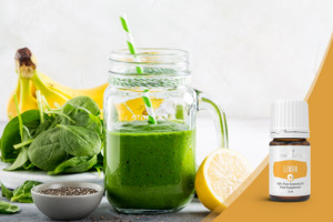 Grüner Smoothie im Glas mit Papierstrohhalm, frischer Spinat, Bananen, Zitrone und Leinsamen mit Lemon+ ätherischem Zitronenöl der Pluslinie von Young Living