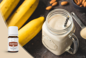 Cremiger Smoothie im Glas mit Papierstrohhalm und frischen Bananen, Mandeln und Cinnamon Bark+ ätherischem Zimtöl der Pluslinie von Young Living