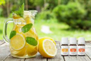 Lemon+, Orange+, and Tangerine+ essential oils with jug of lemon water