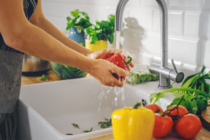 Red peppers being washed in a sink under running water