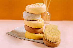 Auswahl an verschiedenen Körperbuttern und festem Massageöl mit Körperbürste