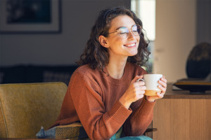 Lächelnde Frau mit Teetasse in der Hand in entspannter Atmosphäre