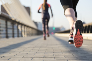 Mujer con ropa deportiva cruzando un puente corriendo