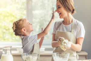 Image of child and parent making dough together in the kitchen.