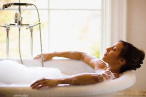 Imagine cu o femei care face baie într-o cadă plină de spumă.