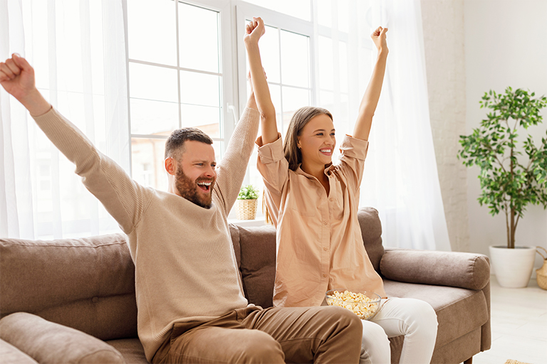 Image of man and woman watching a sports game on TV together.