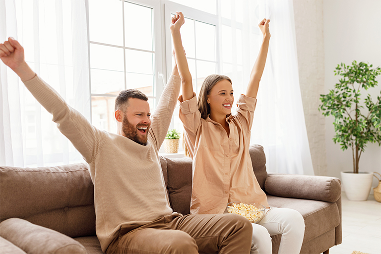 Afbeelding van een man en vrouw die samen sport kijken op tv.