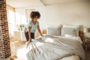 Bild einer Frau, die das Bett macht.