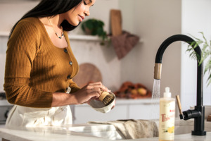A képen egy nő mosogat a Thieves® Washing Up Liquid mosogatószerrel.