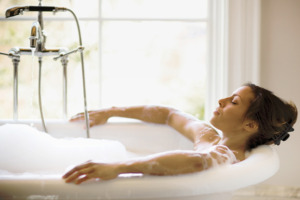 Imagine cu o femei care face baie într-o cadă plină de spumă.