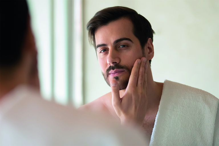 Imagen de un hombre aplicándose aceite en la barba.