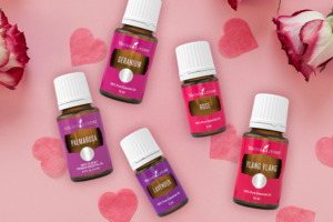 Image of floral essential oils (Lavender, Geranium, Ylang Ylang, Rose & Palmarosa) surrounded by petals and hearts.