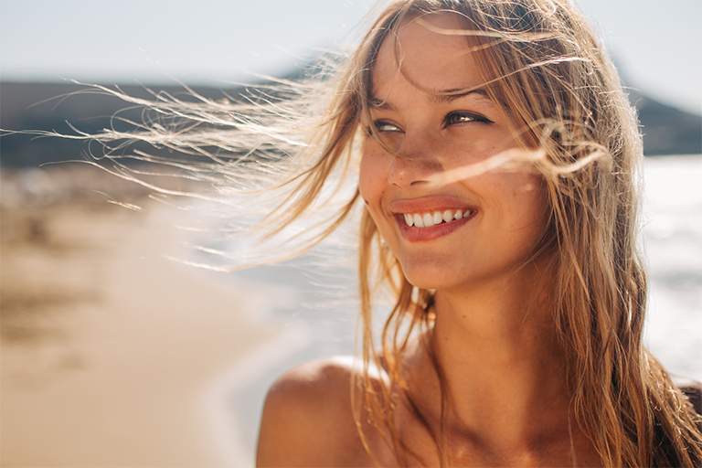 Imagen de una mujer con el pelo ondulado en la playa.