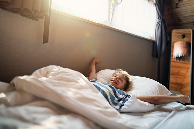 Afbeelding van een jongentje die 's ochtends wakker wordt.