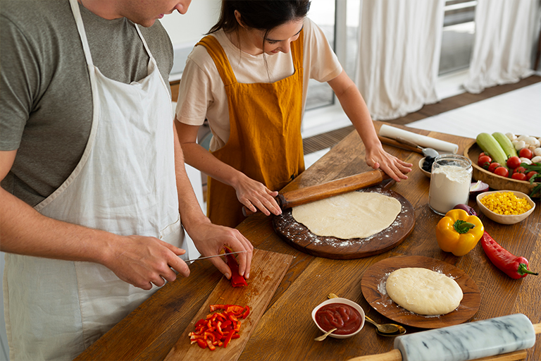 Image of a father and daughter making homemade pizza in the kitchen.