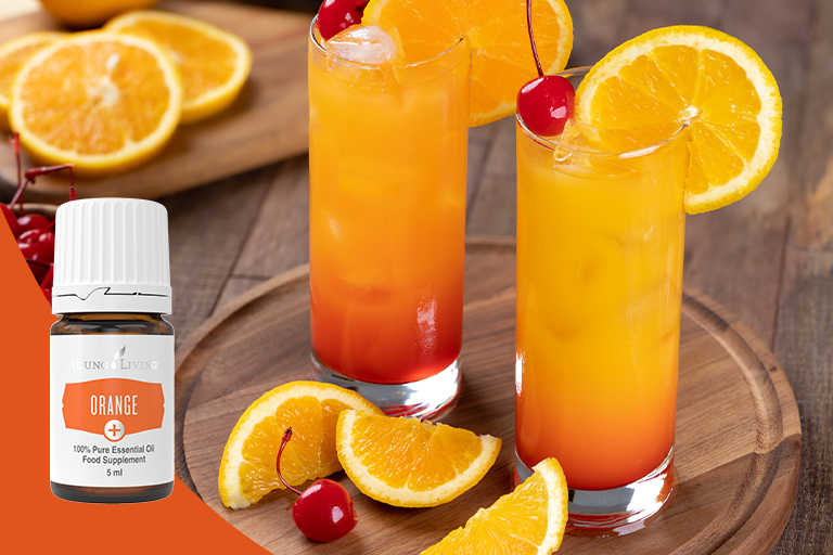 Imagen de una naranja y un cóctel sin alcohol de color rojo con aceite esencial Orange+.