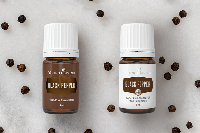 Obrázek esenciálního oleje z pepře černého a esenciálního oleje Black Pepper+ v obklopení kuliček pepře.