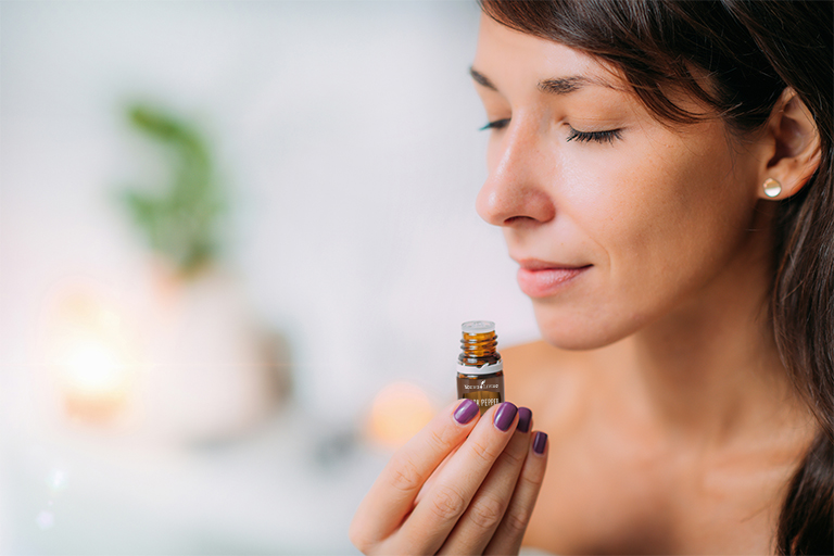 Image of a woman inhaling Black Pepper essential oil directly from the bottle.