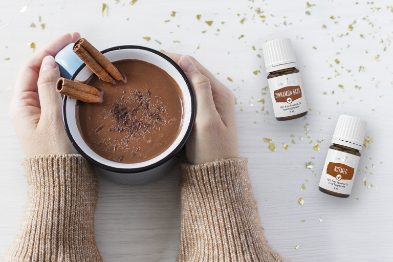 Image of Cinnamon Bark+ and Nutmeg+ essential oils, and hot chocolate garnished with cinnamon sticks.