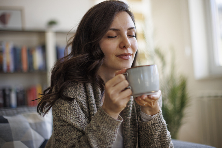 Imagen de una mujer disfrutando de una taza de chocolate caliente.