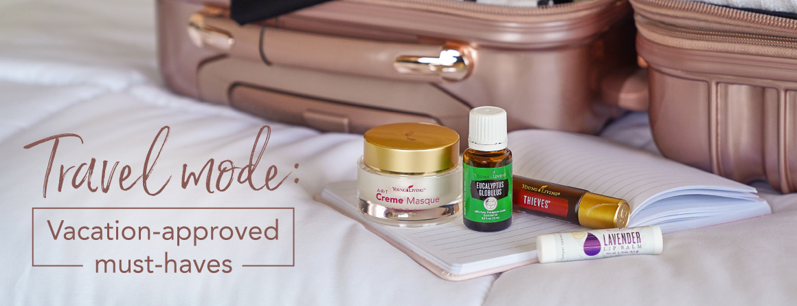 An open suitcase packed with clothes and essential oil products for travel: Breathe again roll on, eucalyptus globulus essential oil, and ART creme masque