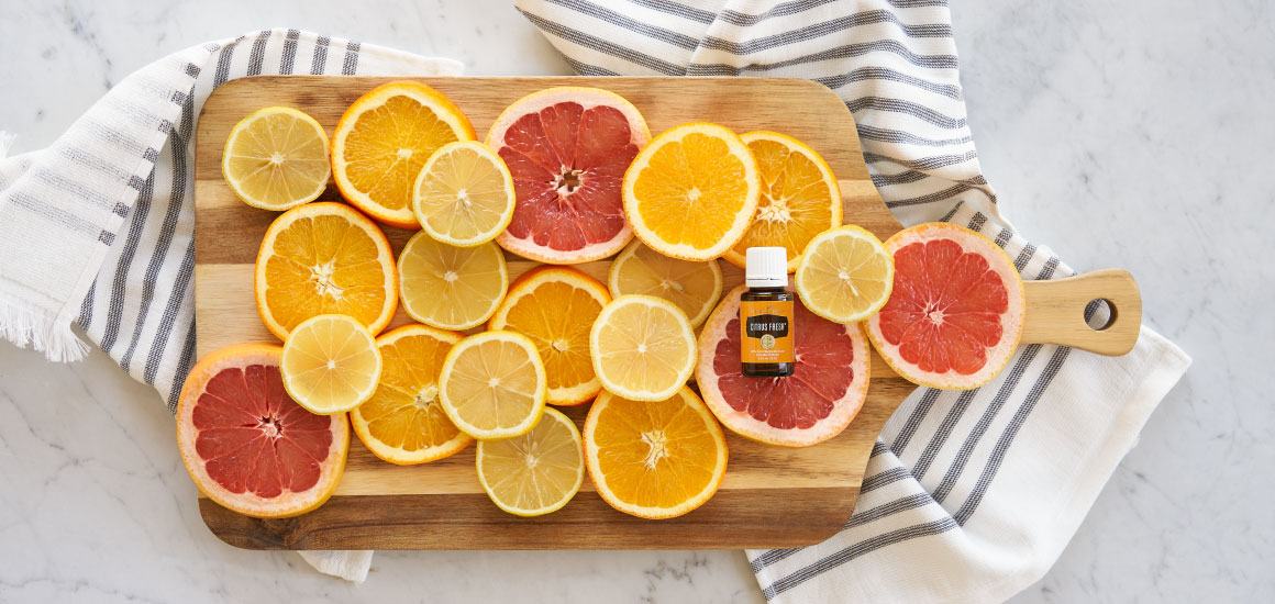 Citrus fruits on a towel and wooden cutting board on a counter top.