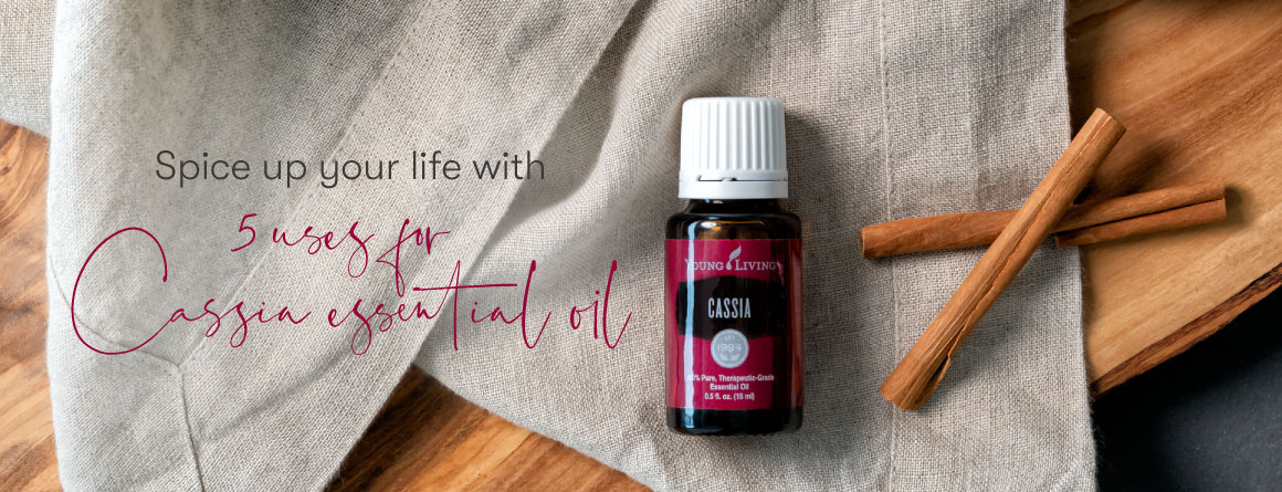 bottle of cassia essential oil surrounded by cinnamon sticks on a linen and wood background