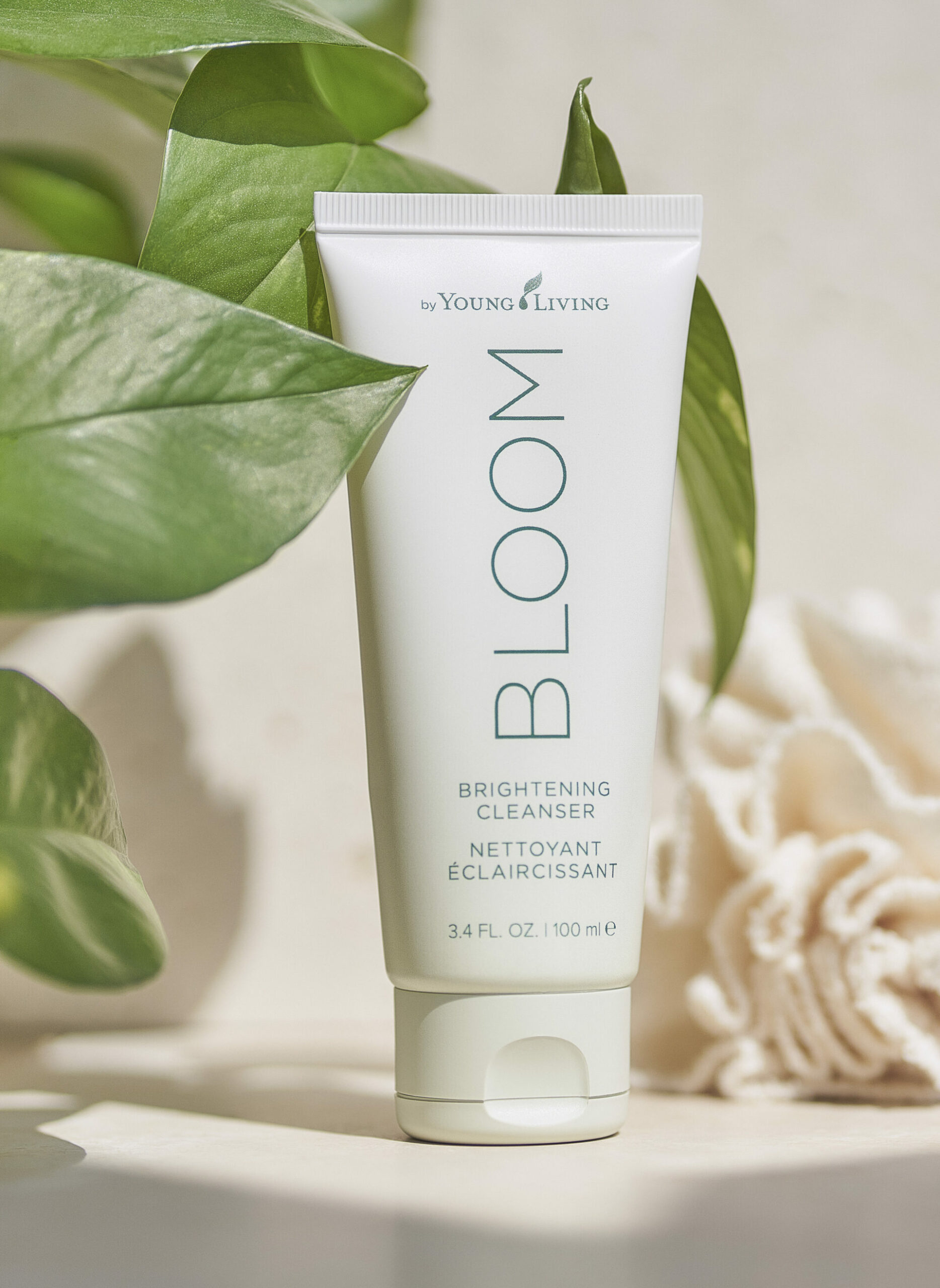 BLOOM Brightening Cleanser sitting on countertop with plan and fabric loofah - Young Living Lavender Life Blog 