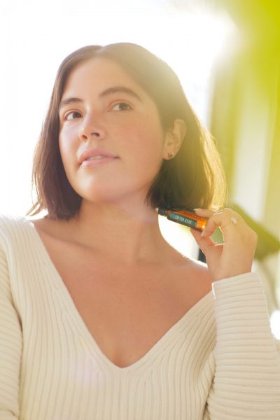 Woman applying Young Living Deep relief essential oil roller on her neck