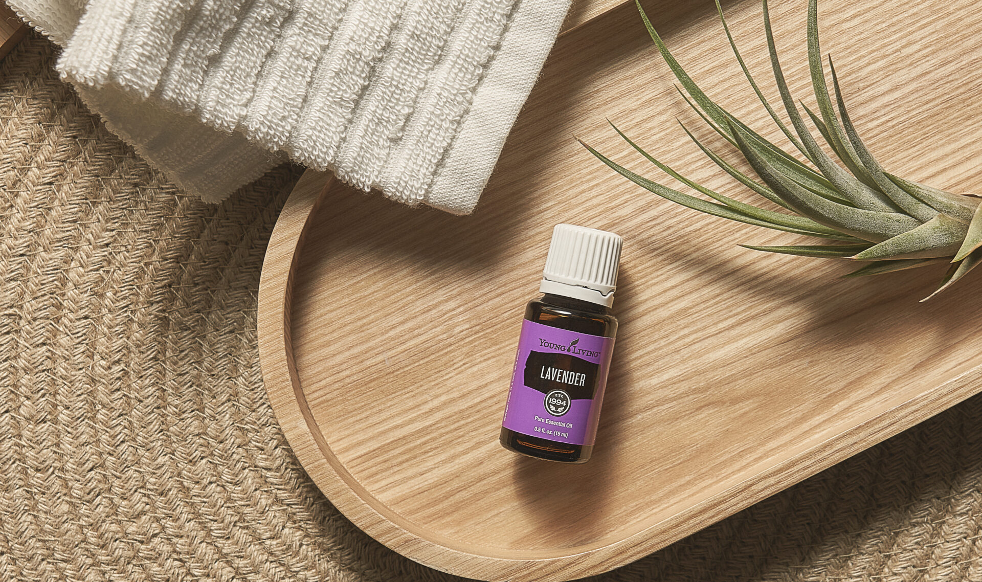 Lavender Essential Oil sitting on wooden tray with plant - Young Living Lavender Life blog