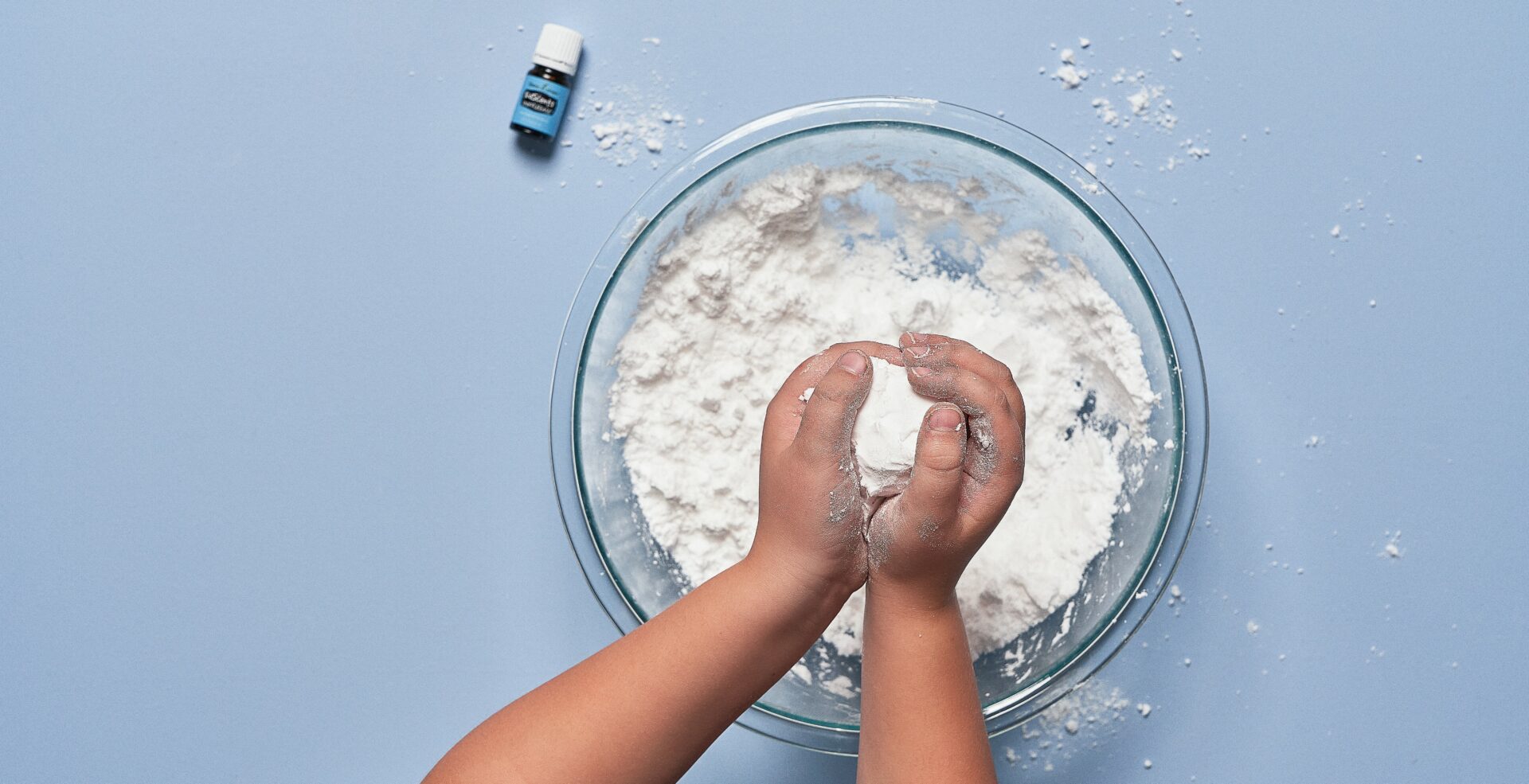 sniffle ease Kid playing with fake snow, KidScents SniffleEase sitting on table - Young Living Lavender Life Blog